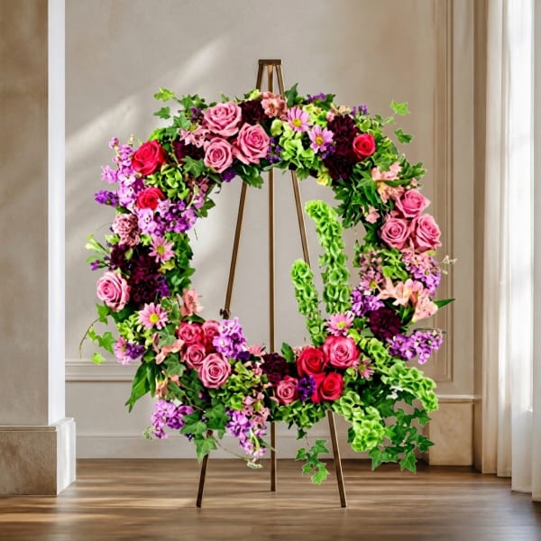 Large floral wreath on a stand with pink and purple flowers