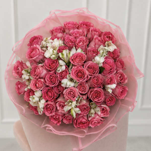 Bouquet of pink roses and white alstroemeria wrapped in pink tissue
