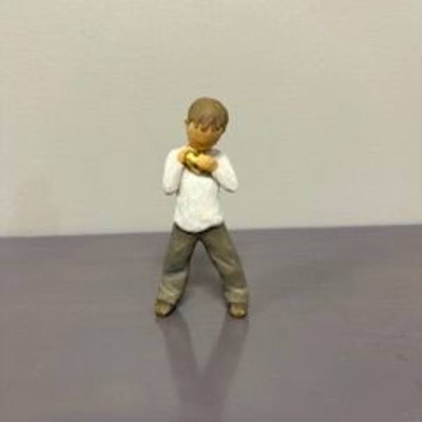 Small figurine of a child standing with hands near the chest