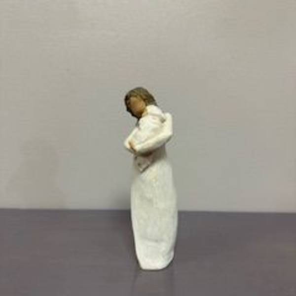 Small figurine of a person in a white dress standing on a plain surface