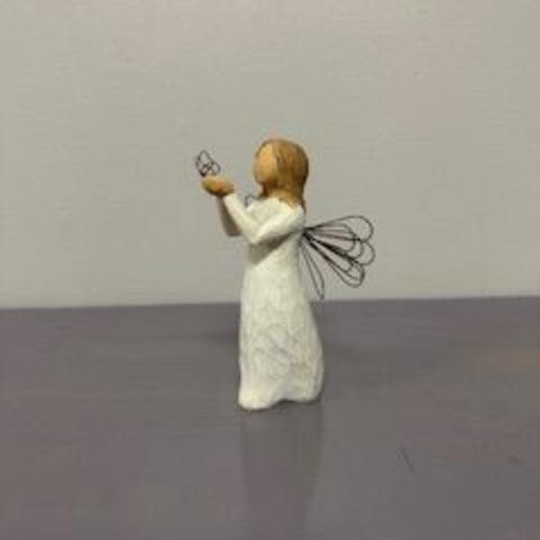 Small angel figurine in a white dress holding a butterfly