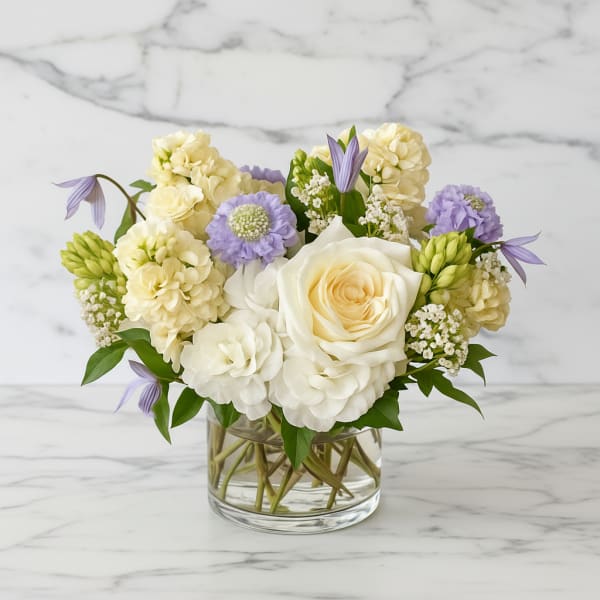 White and lavender flowers arranged in a clear glass vase