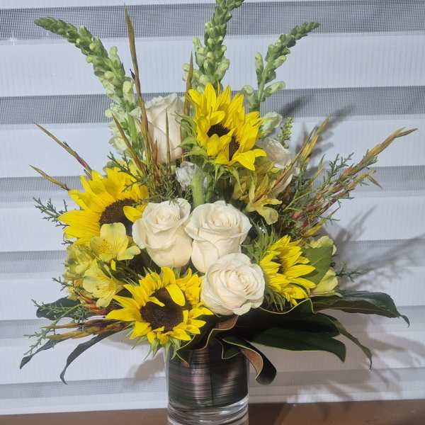 Bouquet of white roses and yellow sunflowers in a glass vase