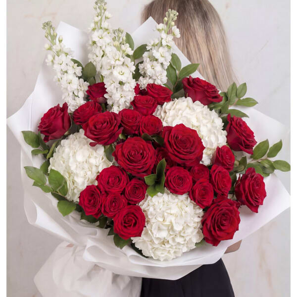 Bouquet of red roses and white hydrangeas wrapped in white paper