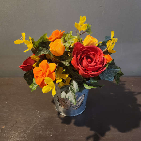 Small arrangement of red, orange, and yellow flowers in a metal pot