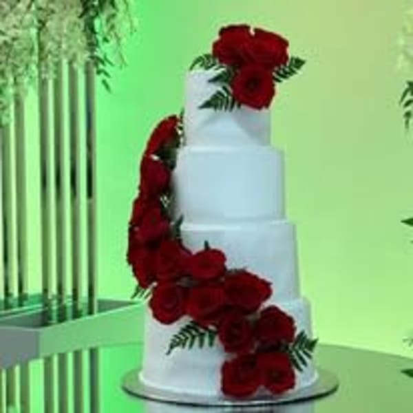White tiered cake decorated with red roses