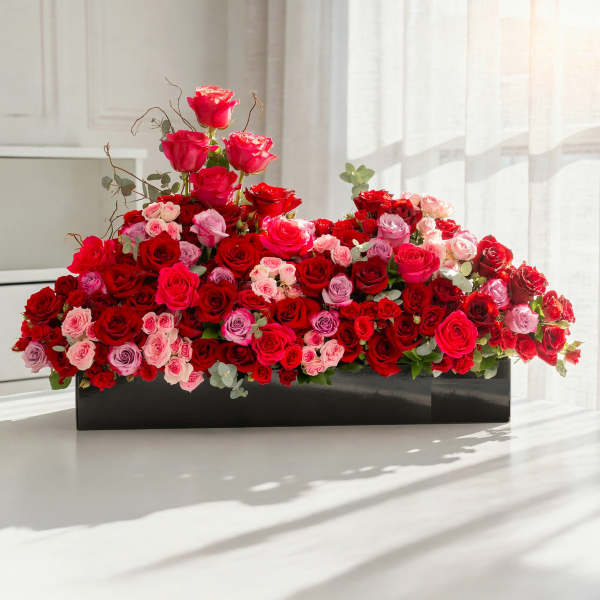 Large arrangement of red and pink roses in a black rectangular box