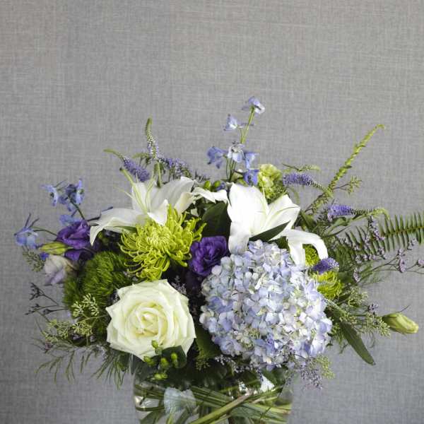 White lilies, roses, and lavender hydrangea in a glass vase