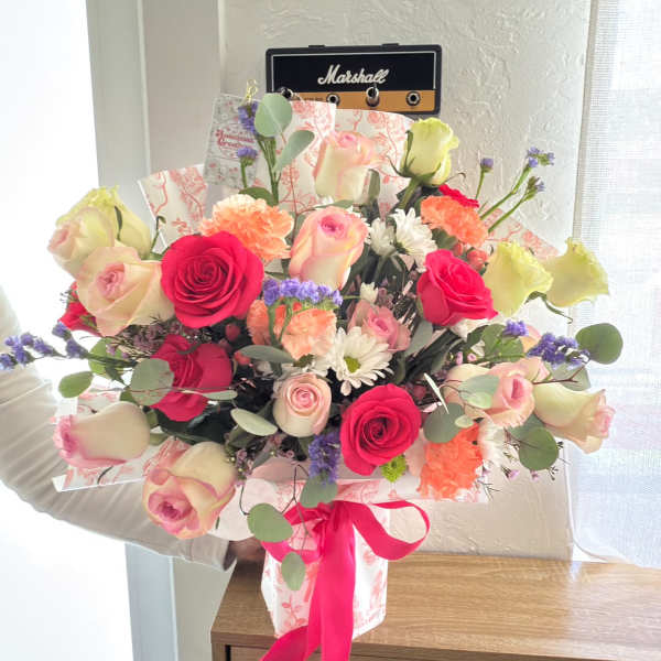 Mixed bouquet of pink and cream roses with carnations and daisies in pink wrap