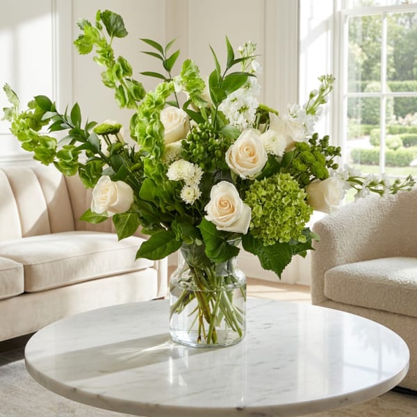 White roses and green flowers in a clear glass vase