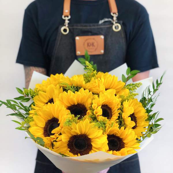 Bouquet of bright yellow sunflowers wrapped in white paper