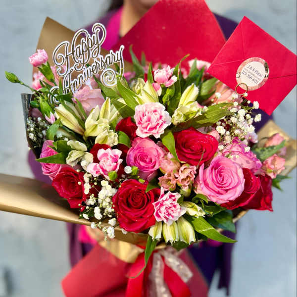 Bouquet of pink and red roses with lilies and carnations, wrapped in red paper