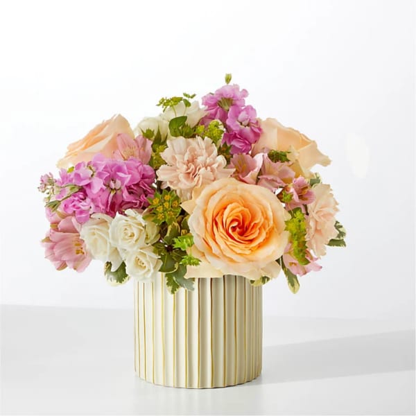 Peach and pink flower arrangement in a ribbed cream vase