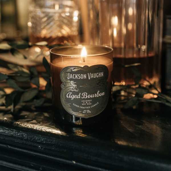 Lit amber candle in a glass jar with a dark label