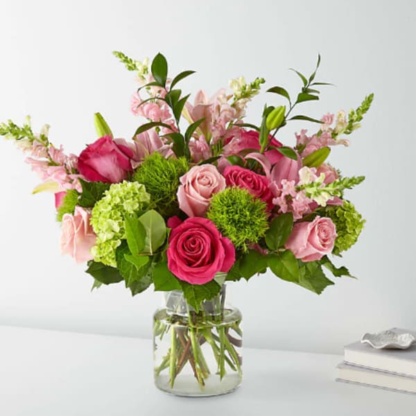 Pink roses and lilies arranged in a clear glass vase