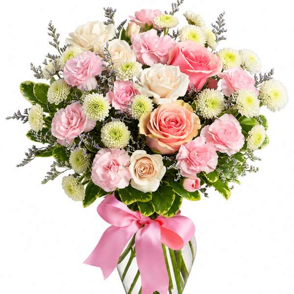 Pink and cream rose bouquet in a glass vase with a pink ribbon