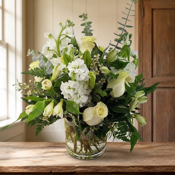 White and pale green floral arrangement in a clear glass vase