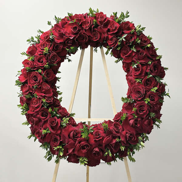 Circular wreath of red roses on a wooden stand