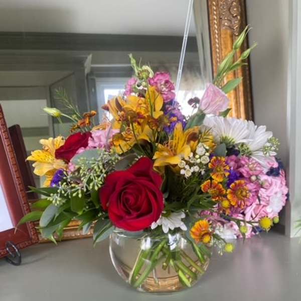 Mixed bouquet with red roses and colorful flowers in a glass vase
