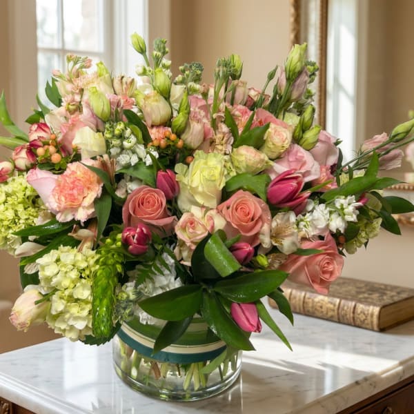 Mixed pink and white flowers arranged in a clear glass vase