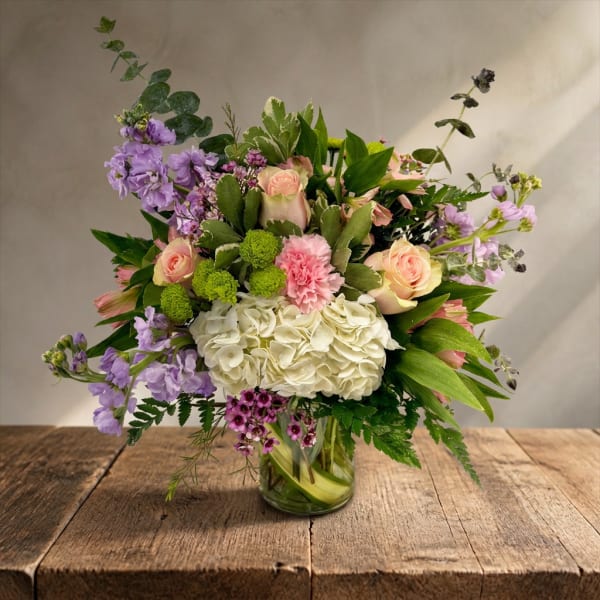 Mixed bouquet of pastel flowers in a clear glass vase
