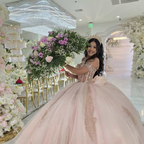 Woman in a pink ball gown holding a large floral bouquet at an event