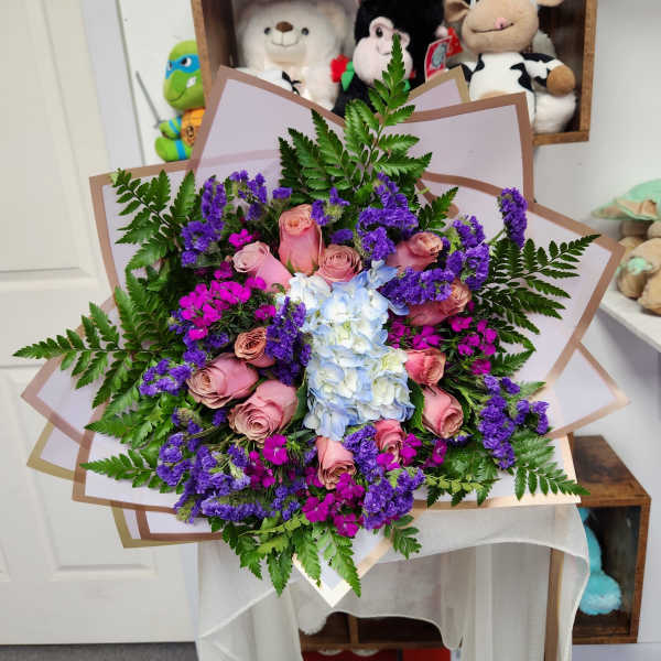Bouquet of pink roses, blue hydrangea, and purple filler flowers