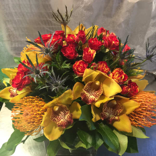 Bouquet of red roses and yellow orchids in a glass vase