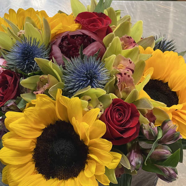 Bouquet with sunflowers, red roses, and blue thistle