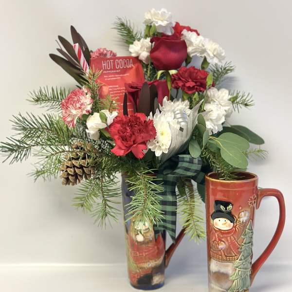 Holiday bouquet with red and white flowers in a tall mug and cocoa packet