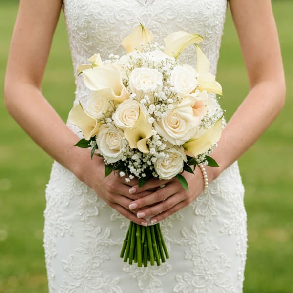 Bride holding a white bouquet with roses and calla lilies