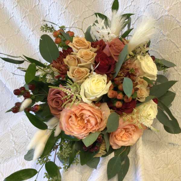 Bouquet of peach and cream roses with burgundy accents