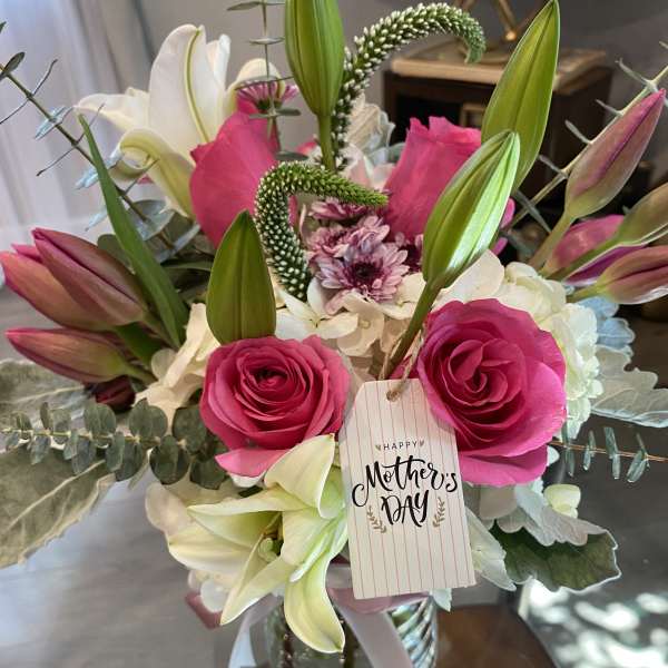 Bouquet of pink roses and white lilies in a glass vase with a Mother's Day tag