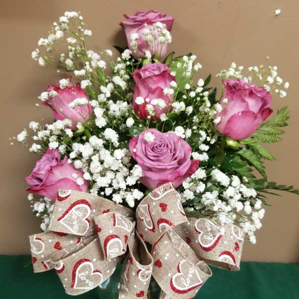 Pink roses with white baby's breath in a glass vase and a heart-patterned bow