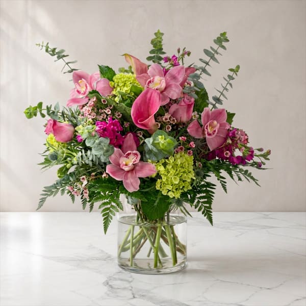 Pink orchids and green hydrangeas in a clear glass vase