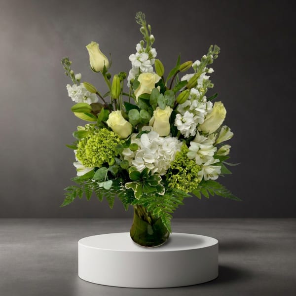 White and pale yellow flowers arranged in a green glass vase