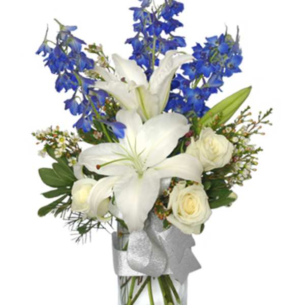 White lilies and roses with blue flowers in a clear vase