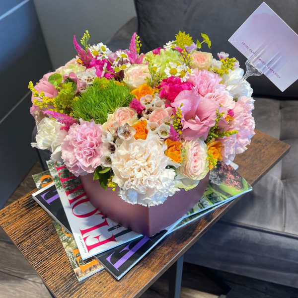 Mixed pastel flower arrangement in a mauve box on a table