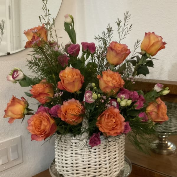 Orange and pink roses arranged in a white wicker basket