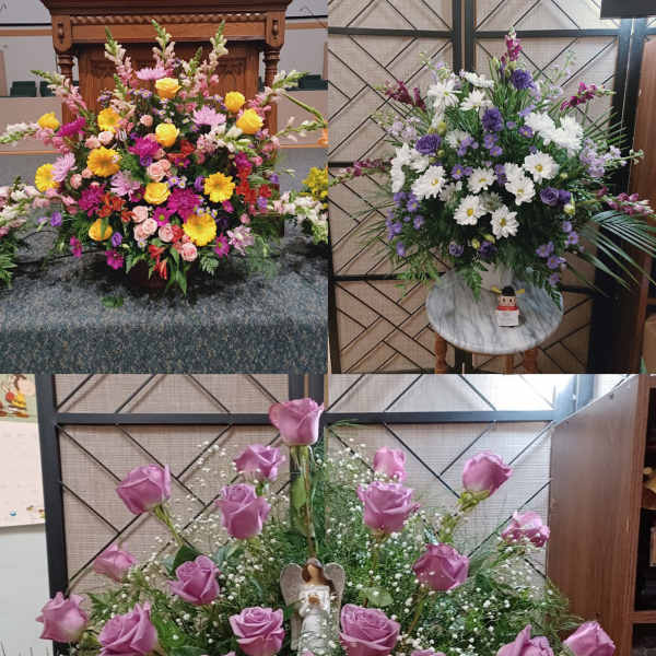 Three large floral arrangements with roses, daisies, and mixed blooms in a church setting.