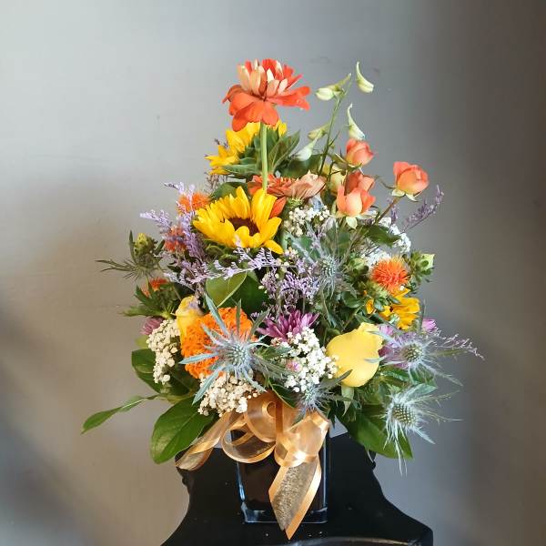 Mixed bouquet in a black vase with orange, yellow, and purple flowers