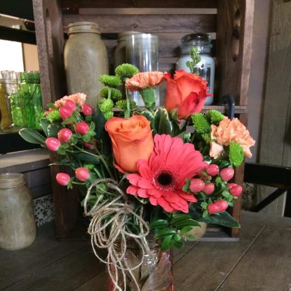 Bouquet of pink and orange flowers in a glass jar vase