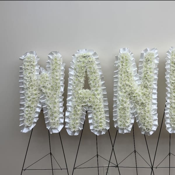 White floral letters spelling "NANDA" on black stands