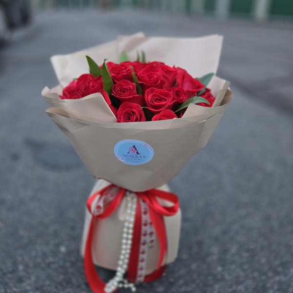 Bouquet of red roses wrapped in beige paper with a red ribbon