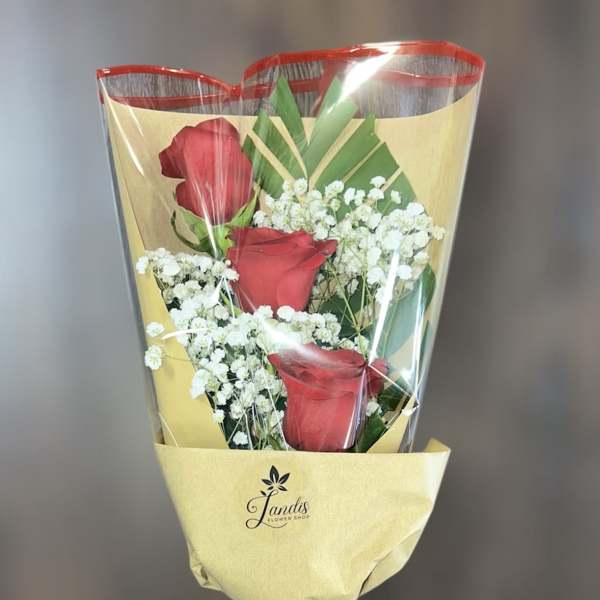 Bouquet of red roses and white baby's breath wrapped in yellow paper