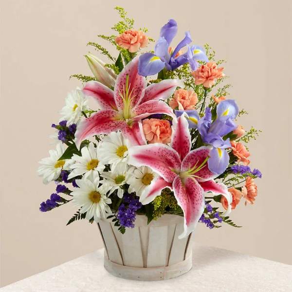 Mixed bouquet with pink lilies, white daisies, and purple irises in a white basket