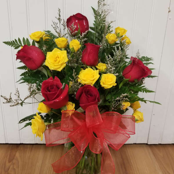 Bouquet of red and yellow roses in a glass vase with a red bow