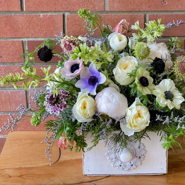 Mixed bouquet of white, lavender, and pink flowers in a white box