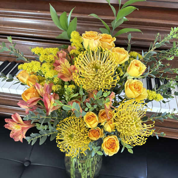 Yellow roses and spider mums in a glass vase with pink alstroemeria
