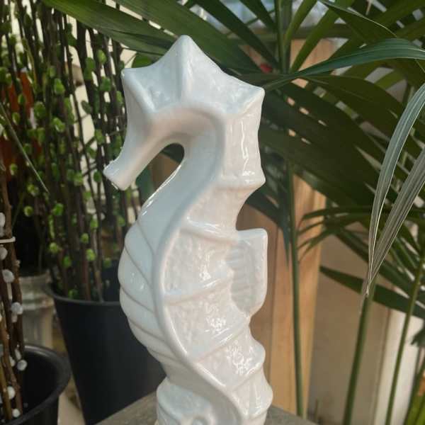 White ceramic seahorse figurine on a textured pedestal